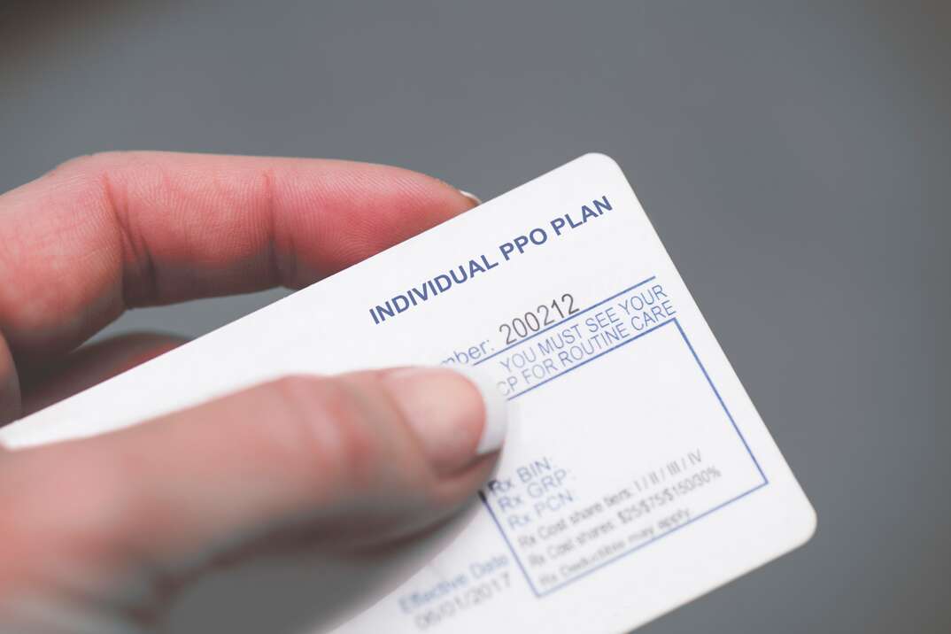 A human hand holds a health insurance card that indicates it is a PPO plan, human hand, health insurance, insurance, health, medical coverage, medical, coverage, PPO plan, PPO, thumb, index finger, finger