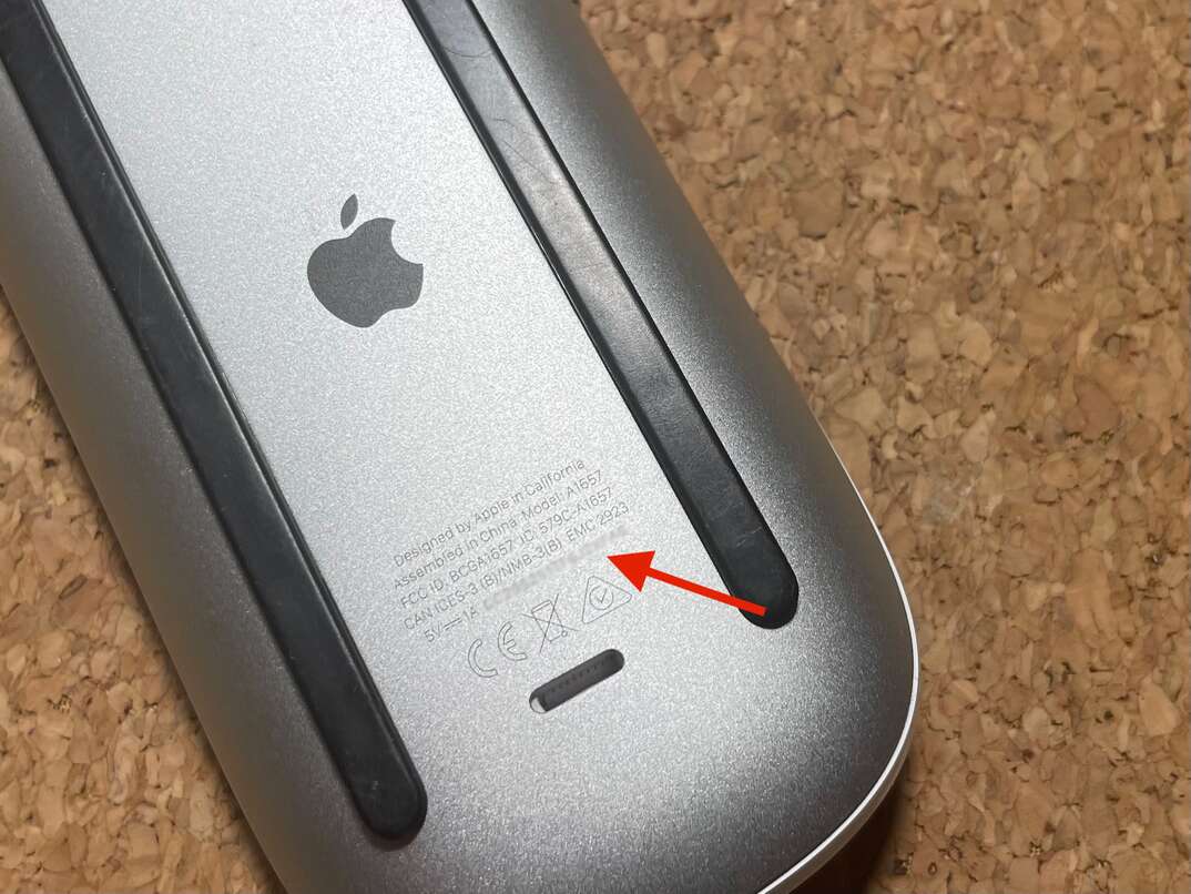 Underside of an apple mouse, with an arrow pointing to a blurred-out serial number