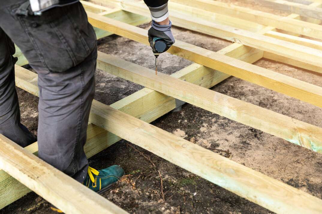 Male construction worker building a wooden deck frame for a resideential terrace deck