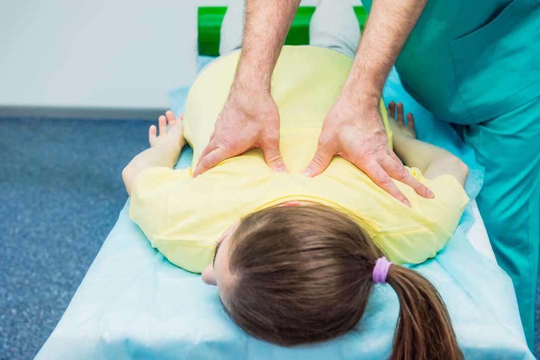 Young female receiving massage from therapist. A chiropractor stretching his patient's spine in medical office. Neurological physical examination. Osteopathy, chiropractic, physiotherapy
