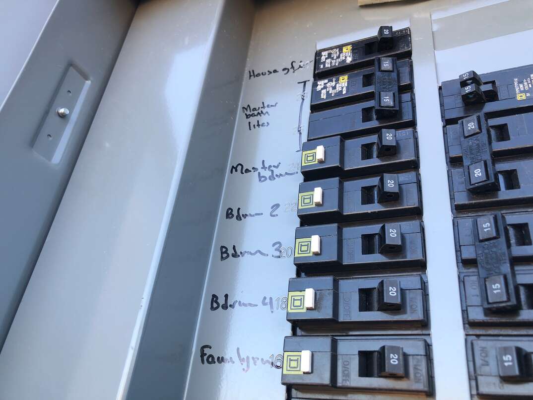 close up of a home electric panel with handwritten labels