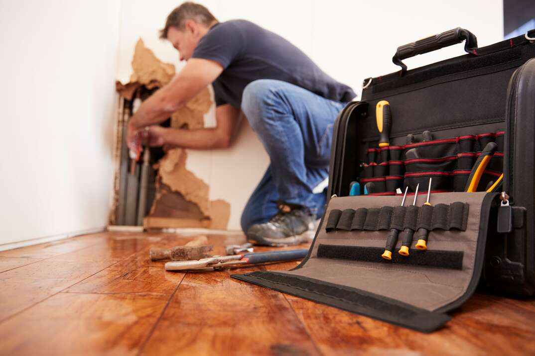 Middle aged man repairing burst pipe