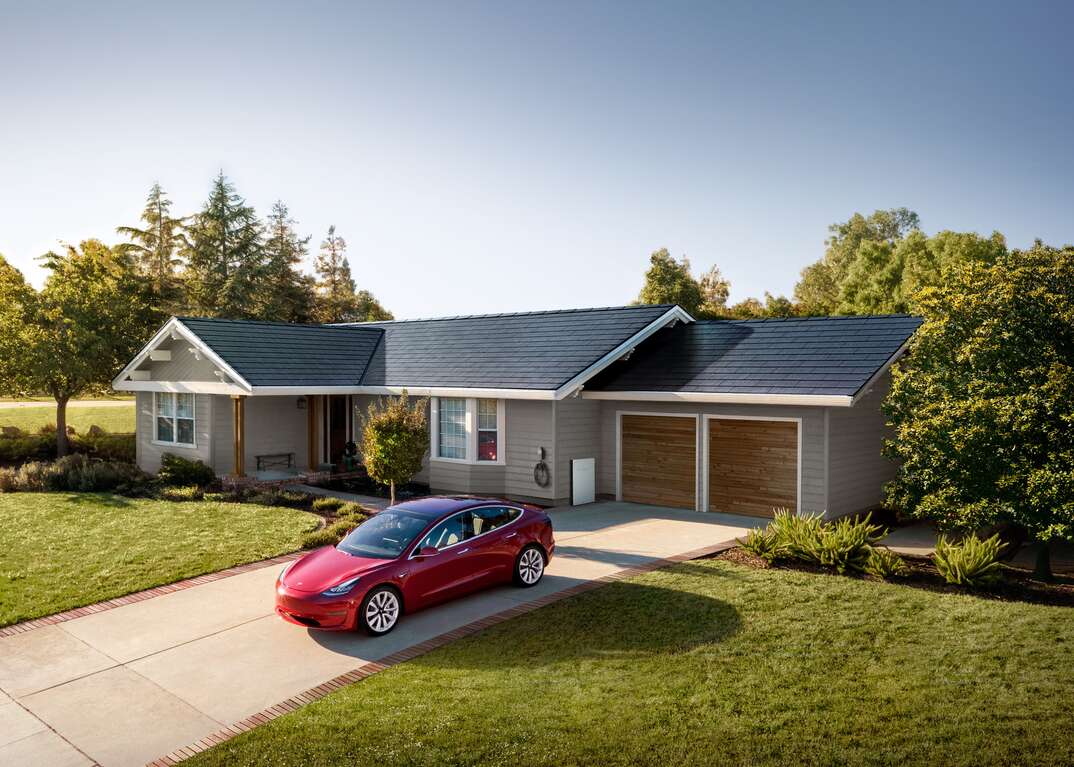 red tesla parked in driveway