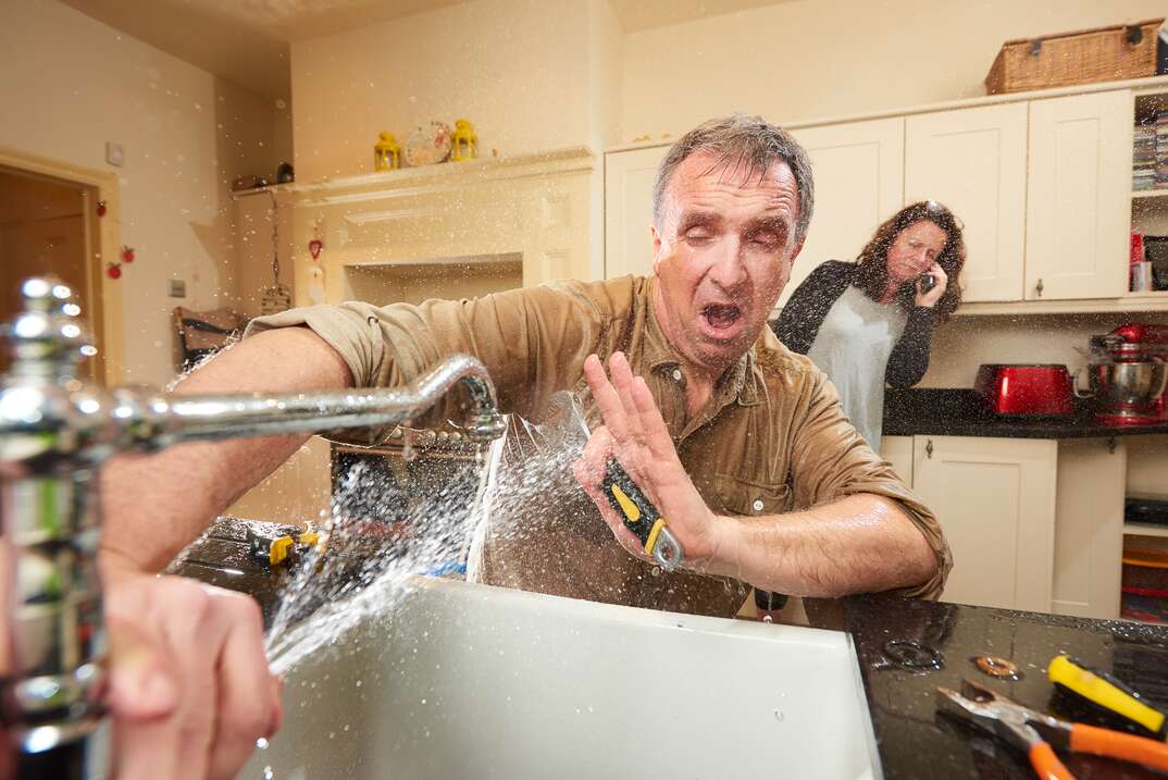 man blocking pipe leaking spurt