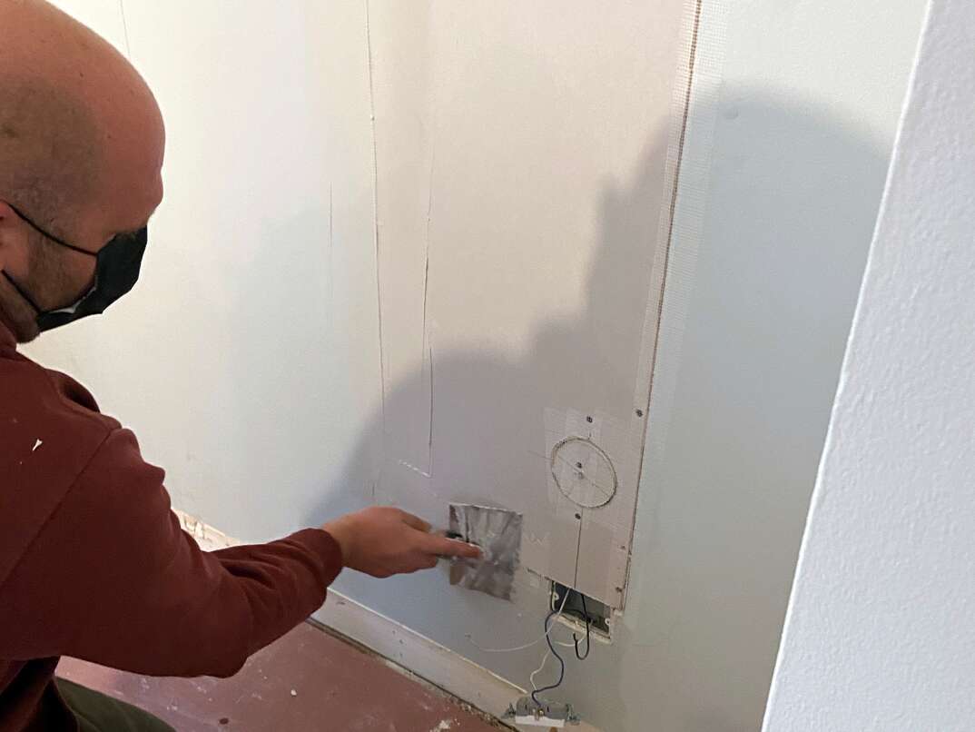 close up of a male contractor applying drywall "mud" to a taped seam of drywall