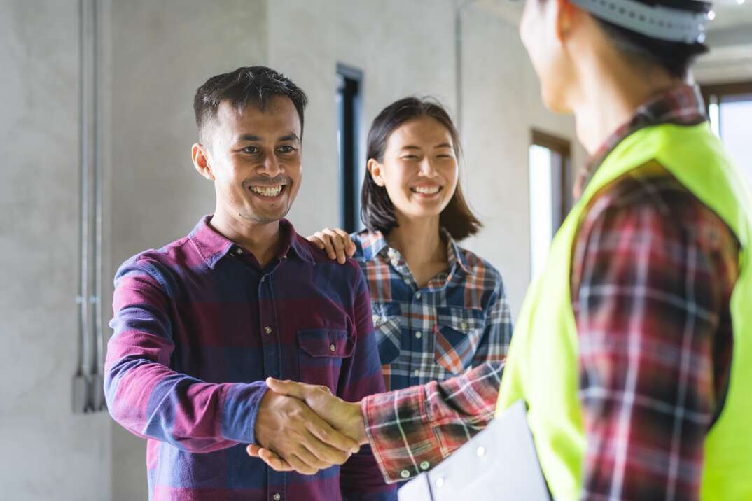 happy man and woman shaking hands with contractor