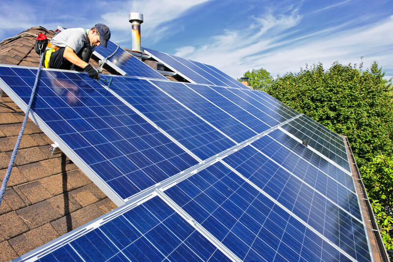 Man installing alternative energy photovoltaic solar panels on roof