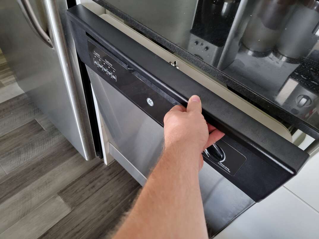 Open door of dishwasher reveals dirty dishes inside as well as where you can find the serial number and model number of the appliance, dishwasher, appliance, kitchen appliance, kitchen, hand, human hand, open door, opening door, interior, inside, dishes, dirty dishes, serial number, model number