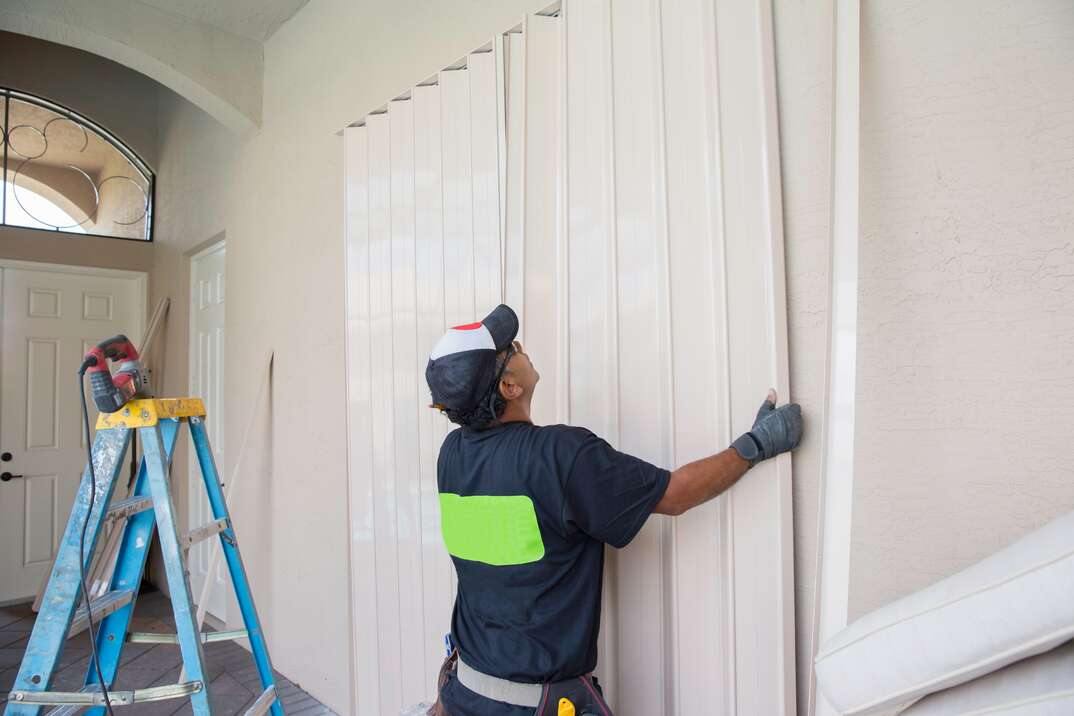 Man installing tall metal Hurricane Shutters