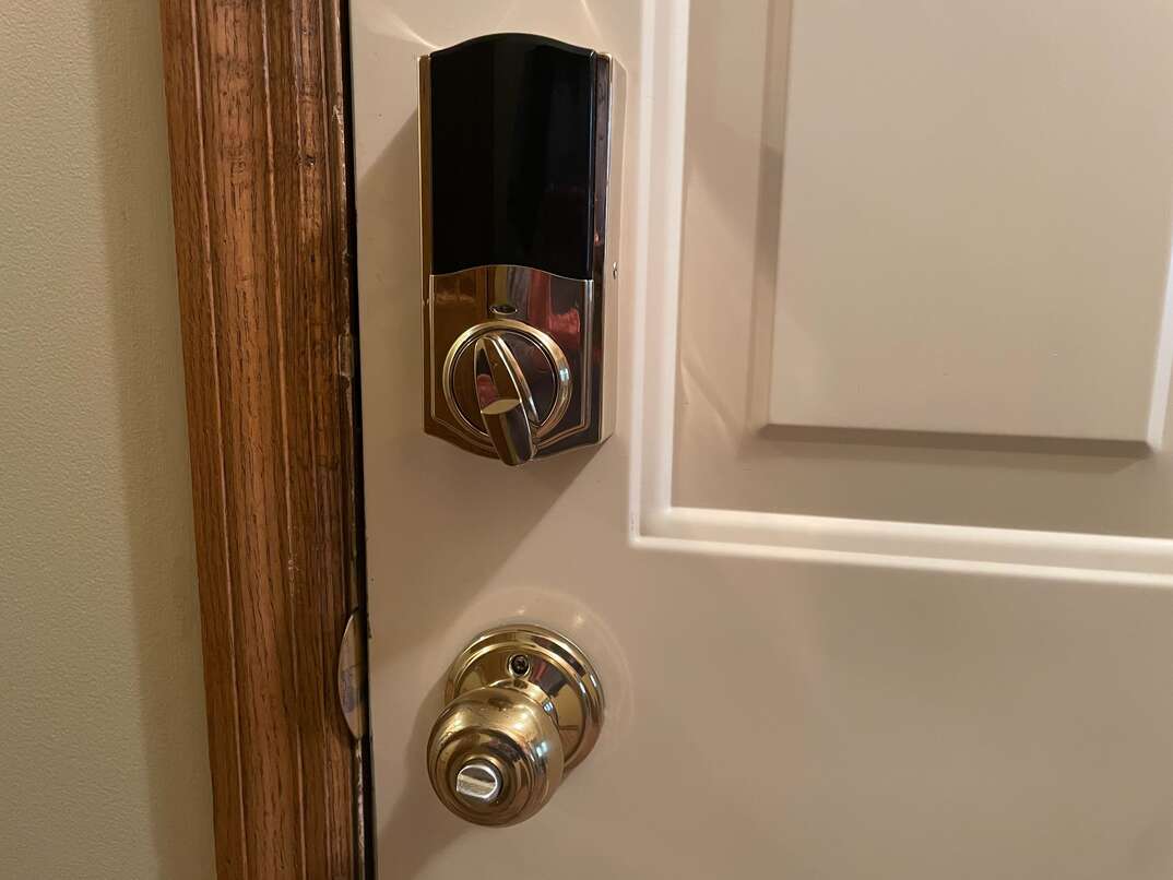brass smart lock on a white door with a brass doorknob