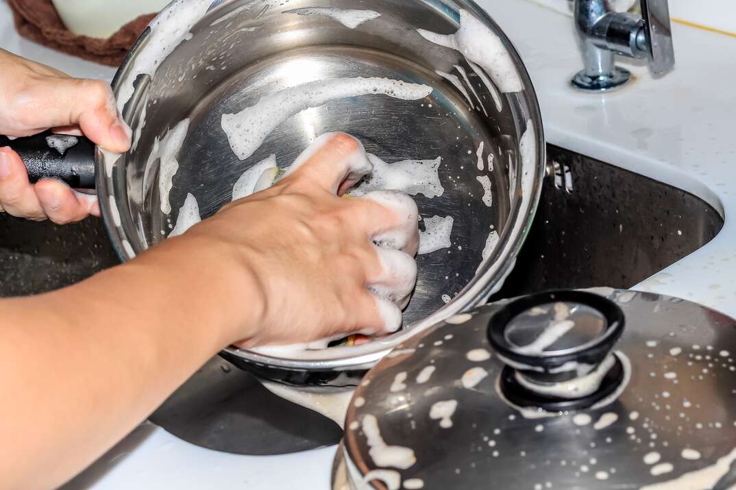 closeup washing frying pan pot in the sink