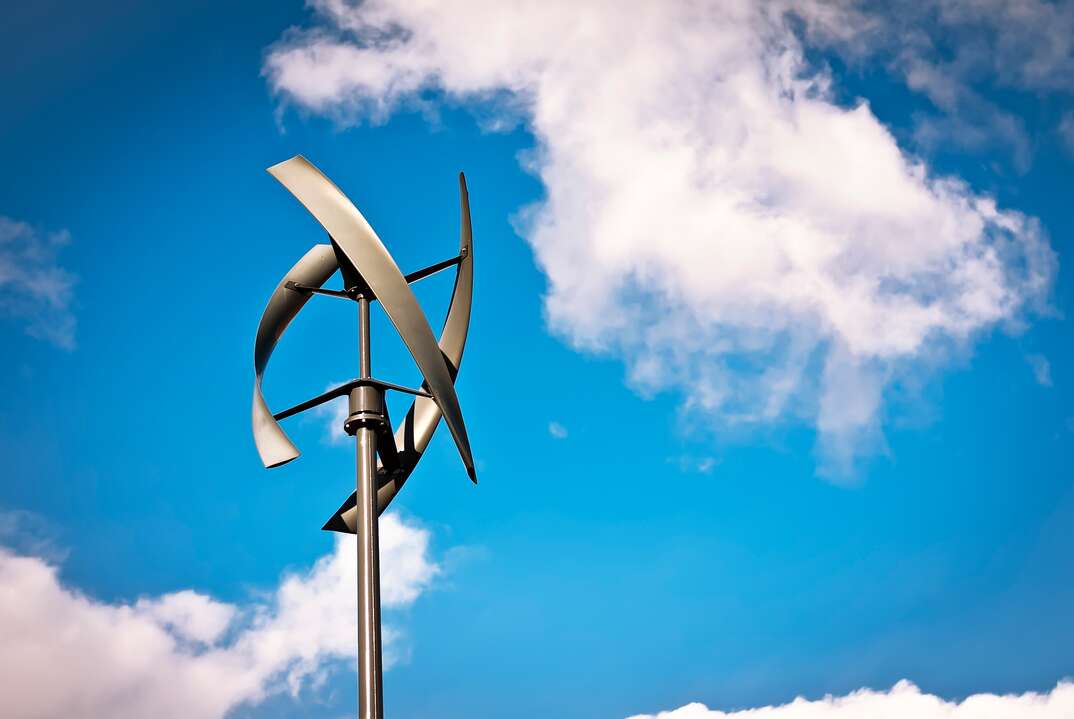 A motionless Vertical Axis residential Wind Turbine with a clear blue sky in the background