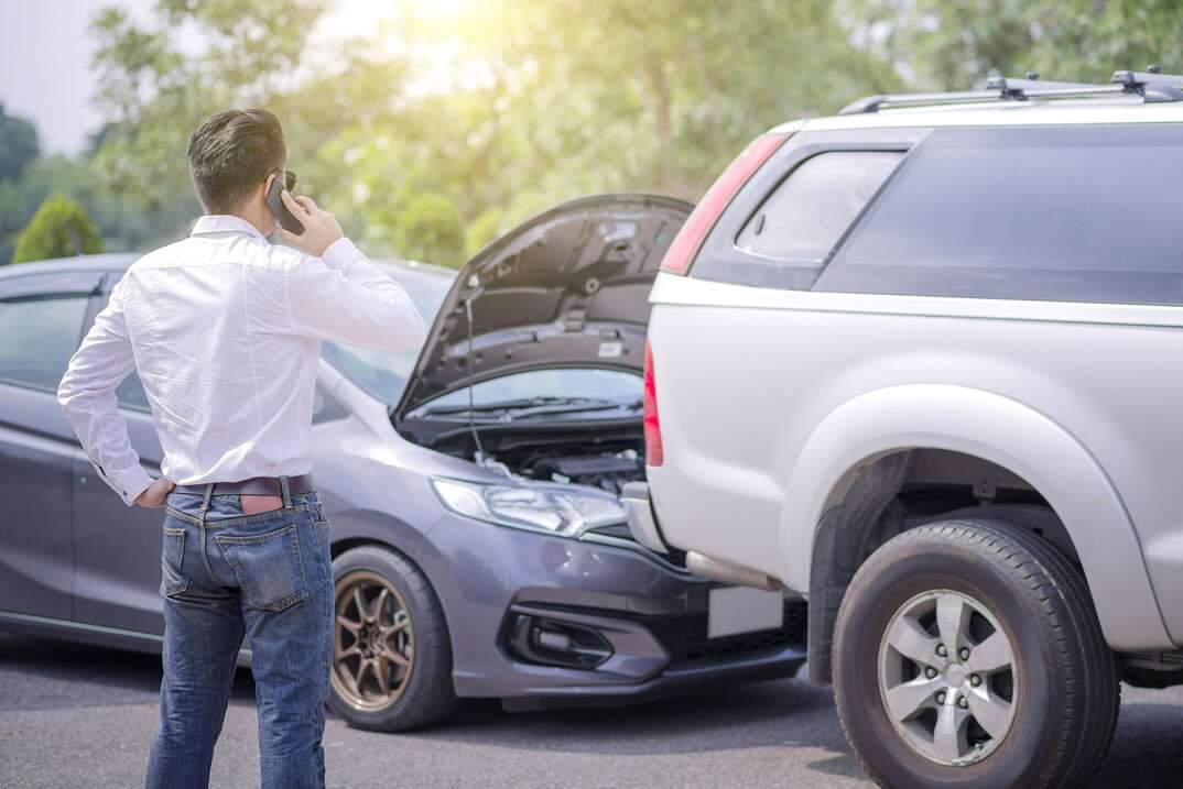 person calling insurance after car fender accident