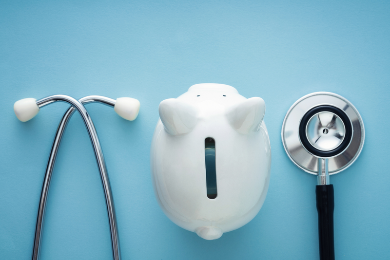 A stethoscope and a piggy bank sit against a light blue background to signify health care insurance or savings, piggy, piggy bank, bank, stethoscope, light blue background, light blue, money, health insurance, health coverage, health plan, medical insurance, medical, insurance, coverage, health