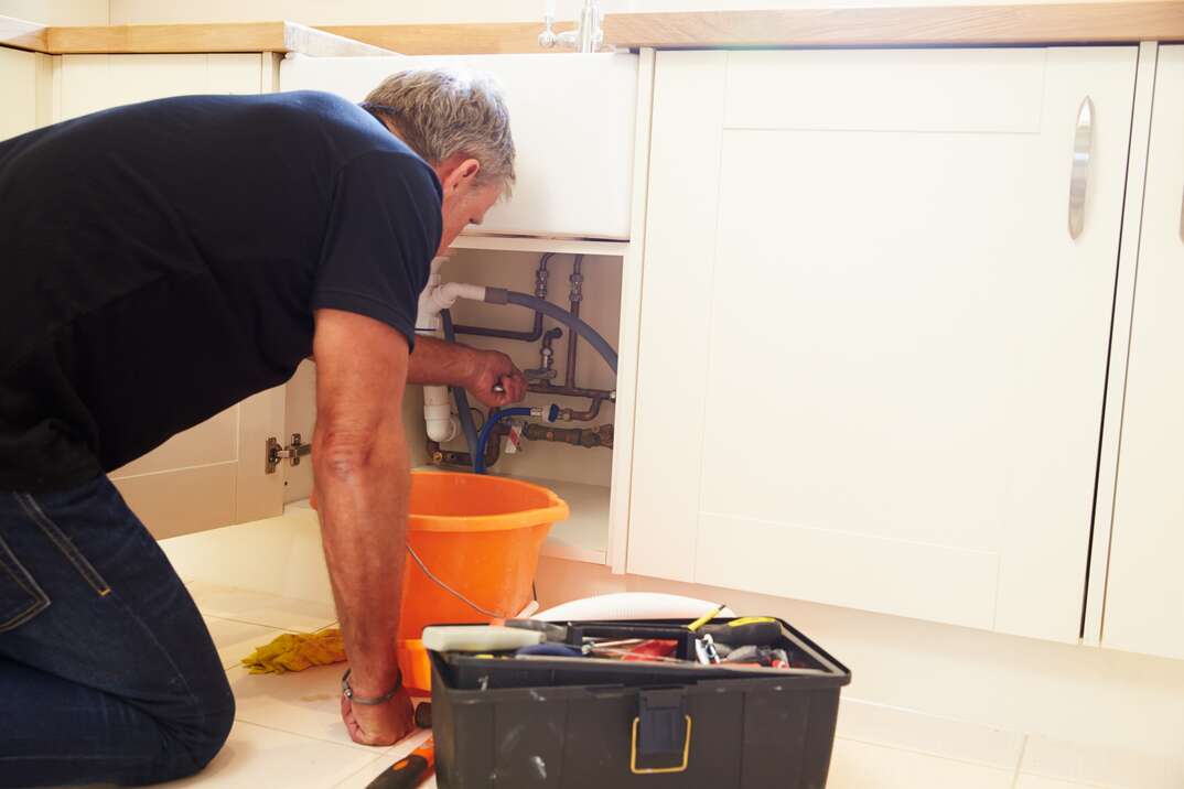 Middle aged male plumber fixing a kitchen sink