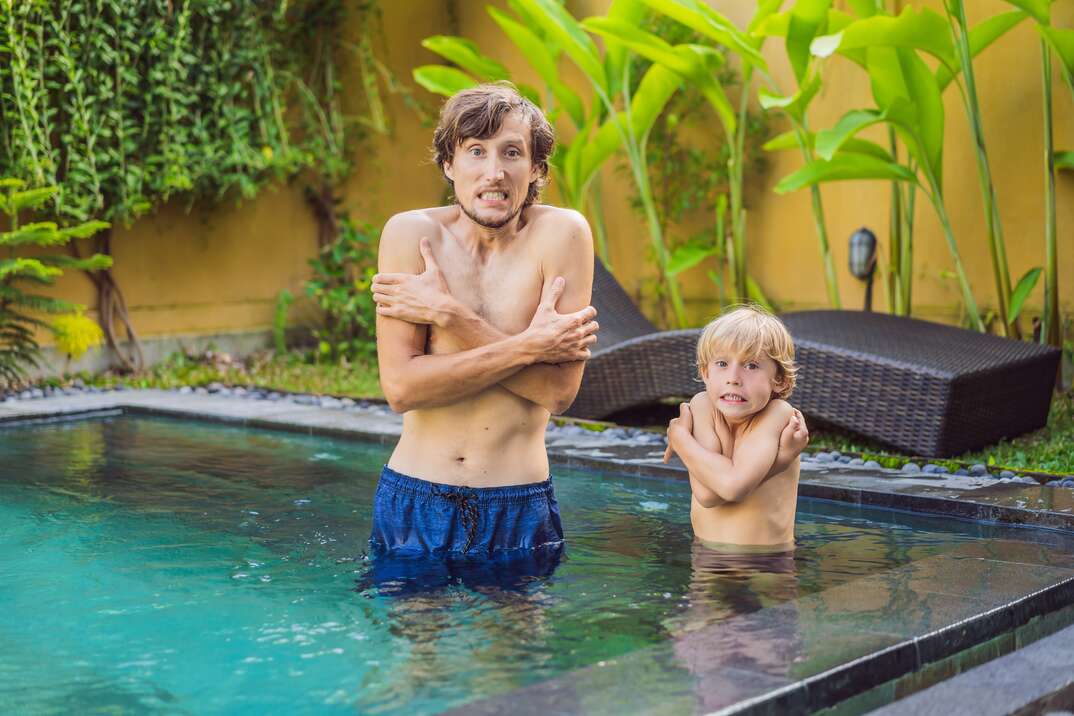 A man and his son shiver in a cold swimming pool 