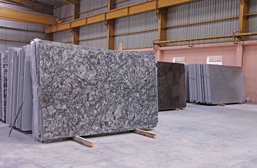 Stacks of different color granite slabs at a warehouse