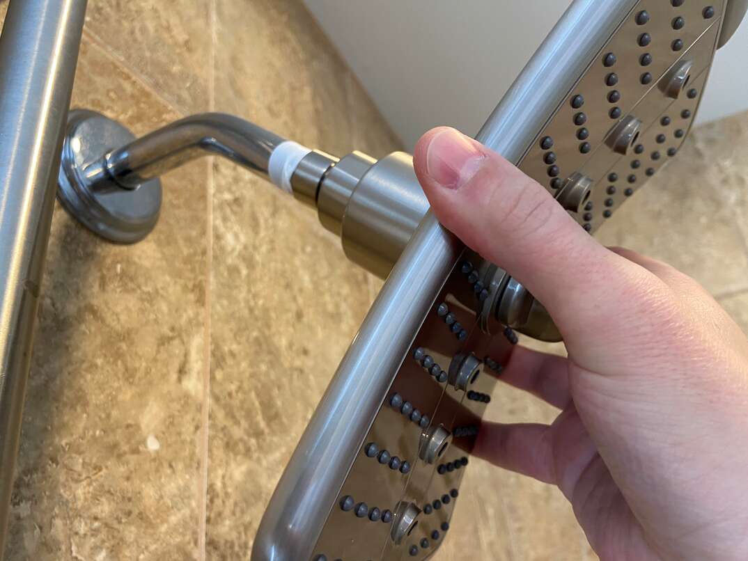 close up image of a new shower head being installed in place of an existing fixture 