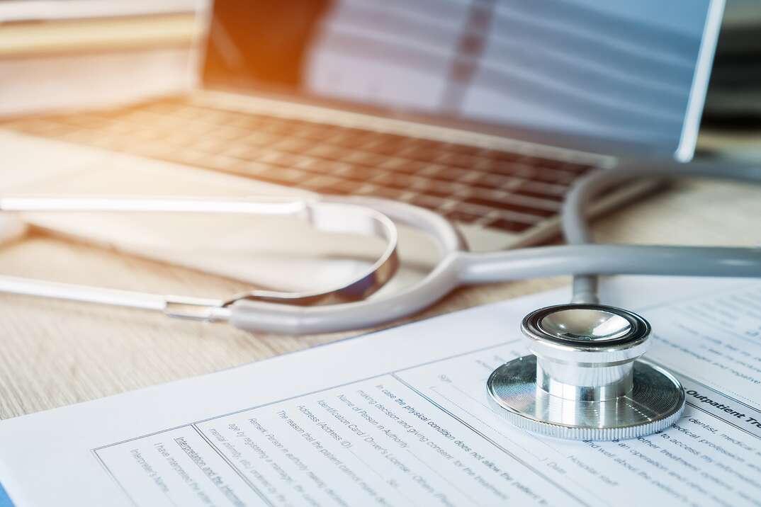 Healthcare and medical concept, Stethoscope on prescription clipboard record information paper with internet laptop computer at Doctor working  on busy desk hospital office, top view selective focus