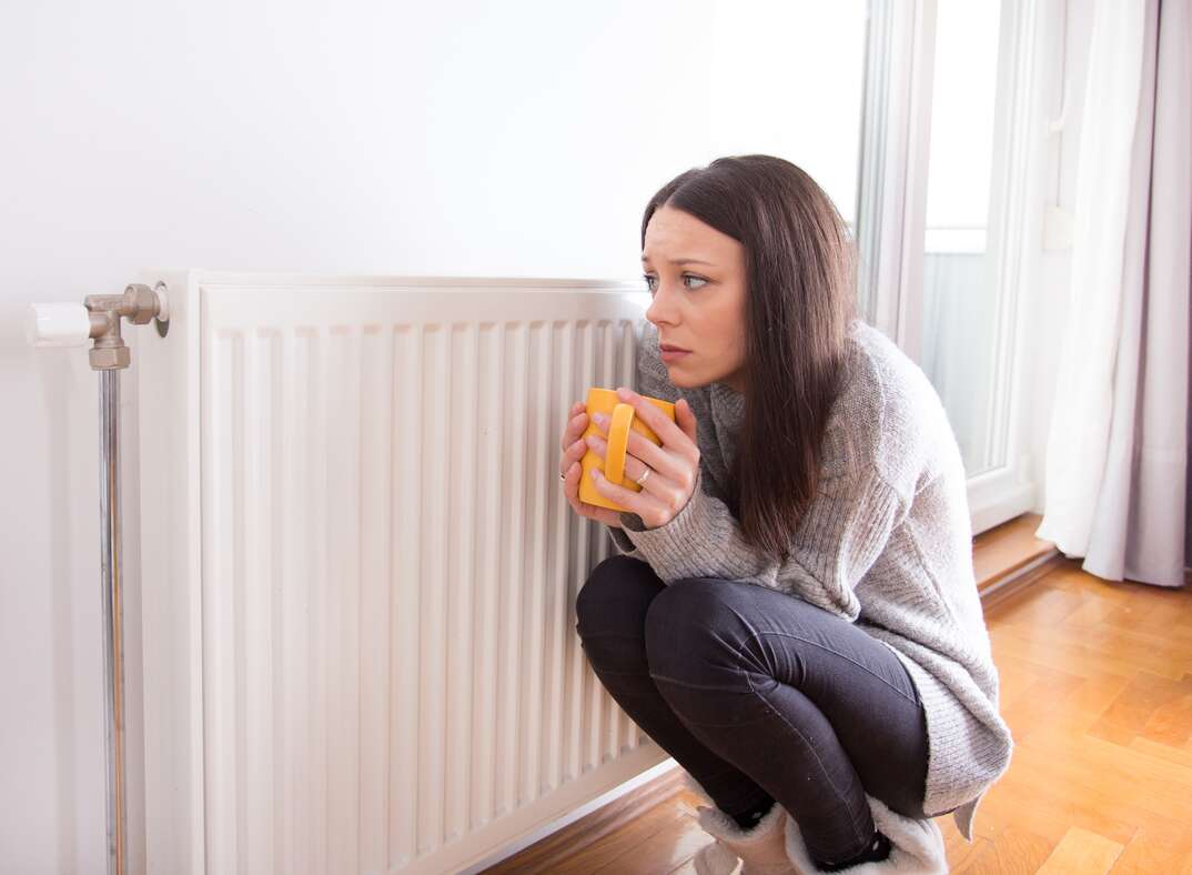 cold woman next to heater