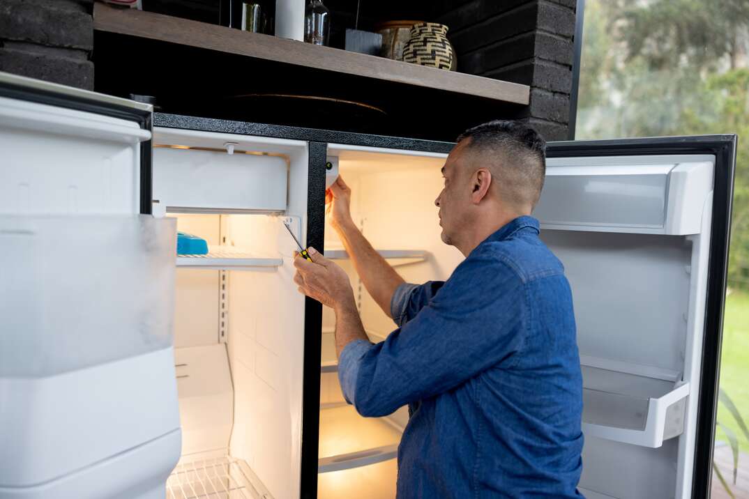 Handyman fixing a fridge at a house