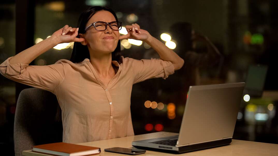 Woman covering ears, irritated with noise in office, nervous breakdown at work