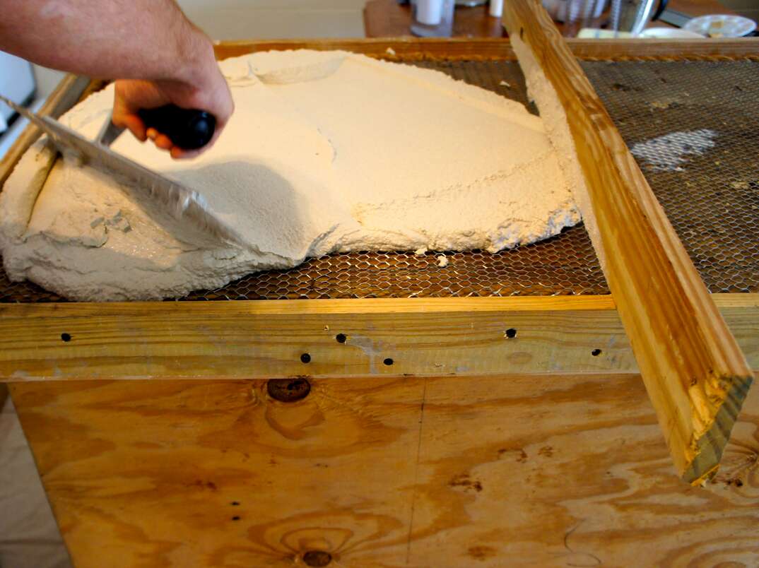 DIY concrete countertops  A trowel spreads concrete over a form to create a kitchen counter 