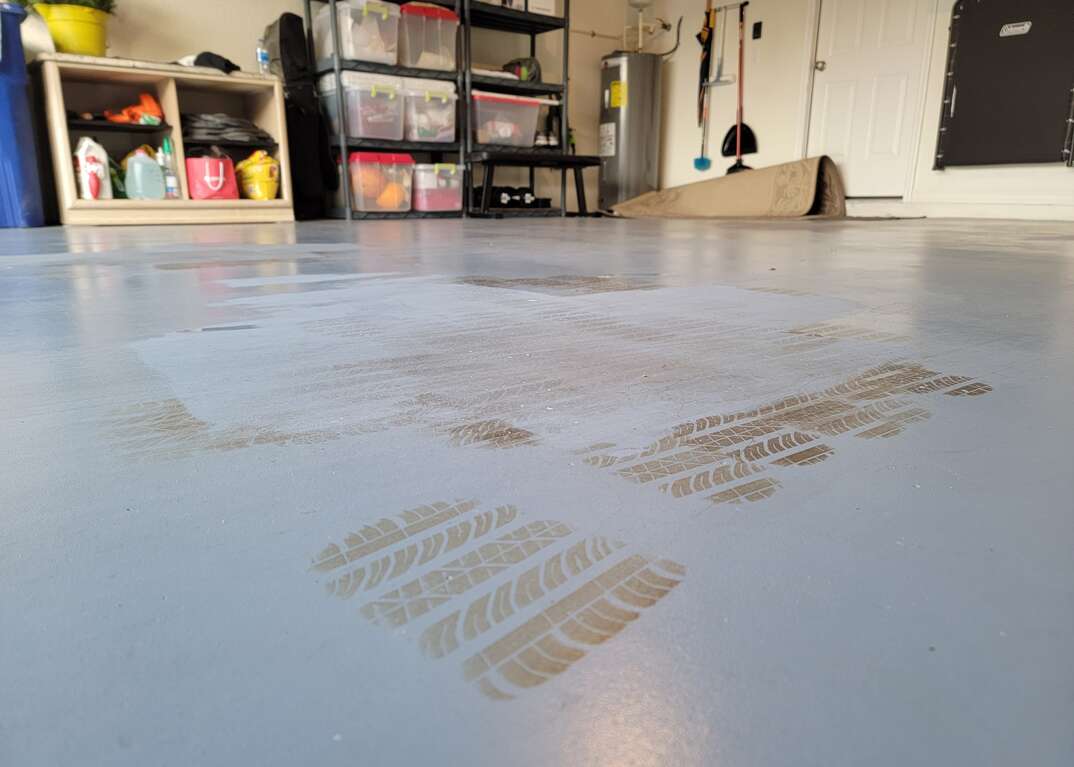 Black tire marks are shown on the gray epoxy garage floor of a residence, tire marks, marks, tire, tires, concrete floor, concrete, epoxy, epoxy floor
