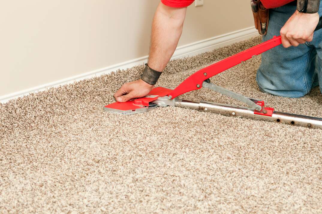 Installer Using Carpet Stretcher on New Bedroom Floor