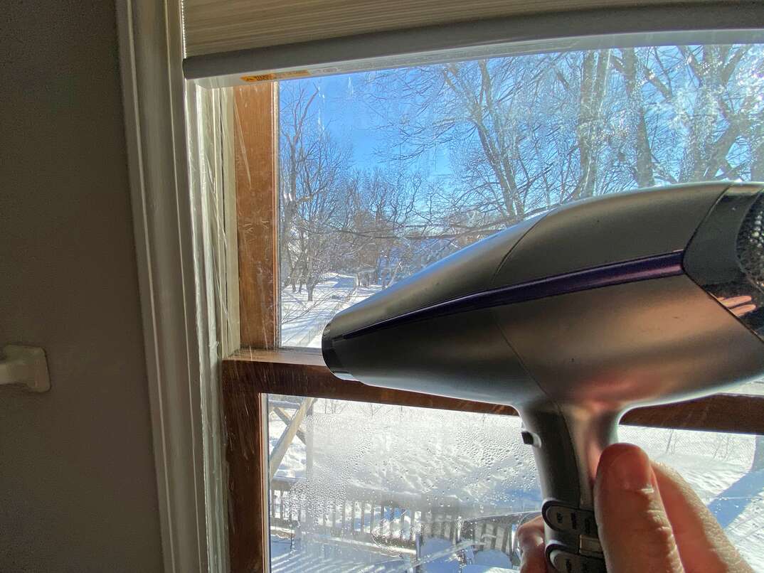 a hair dryer is used to tighten and seal plastic window insulation to an old wood window