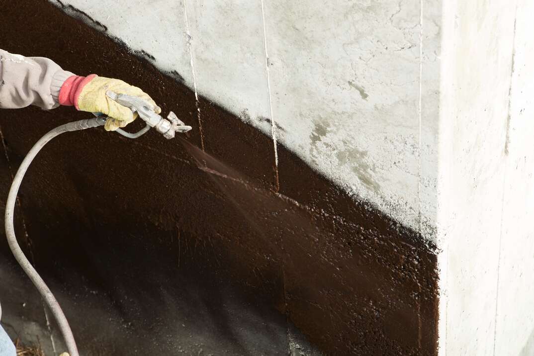 Worker Waterproofing a new House Foundation
