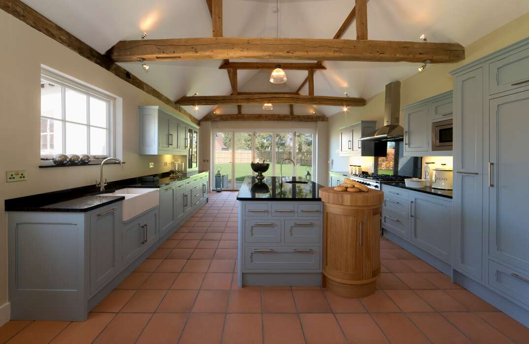 photo of a modern Farmhouse Kitchen with blue cabinets and red terracotta flooring 