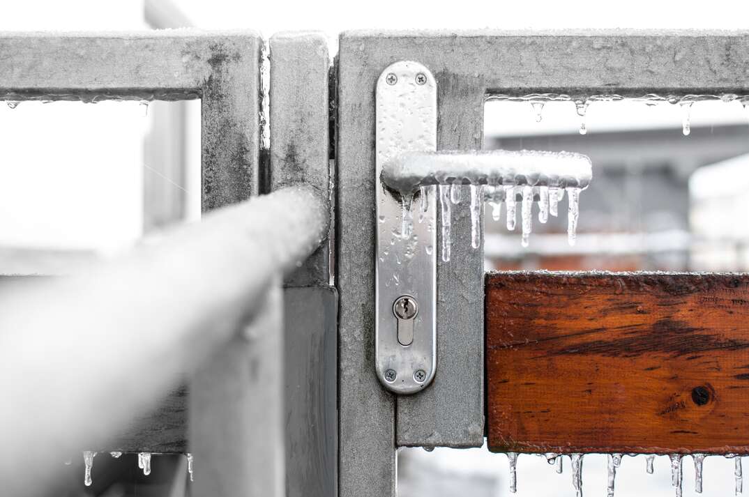 a frozen door handle with small icicles hanging from it.