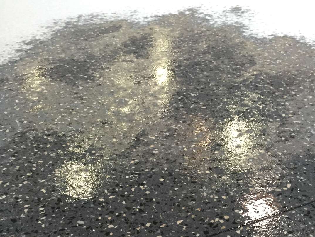 A recently sanded Terrazzo floor with water splashed to show the floor color 