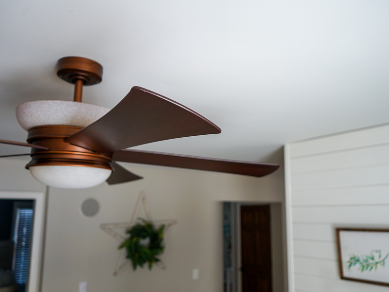 Brown ceiling fan hangs near a neighboring wall