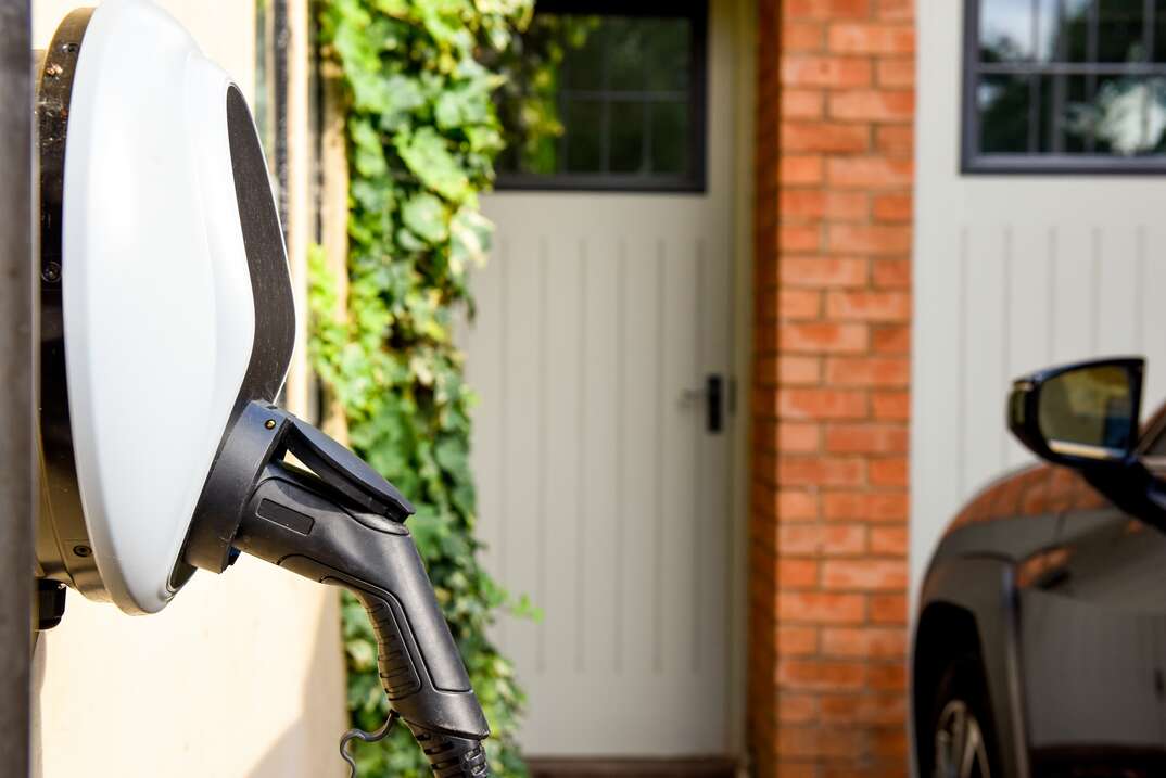 Wall mounted car charging unit to supply power to electric vehicles with copy space on house wall