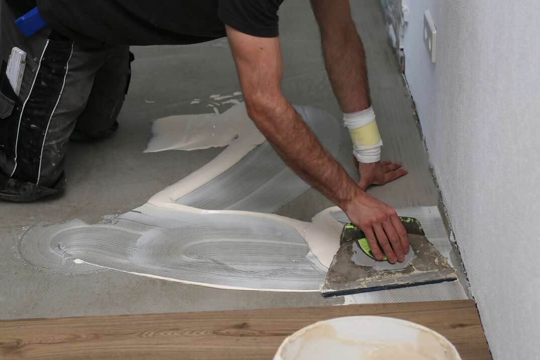 The worker installing new vinyl tile floor.