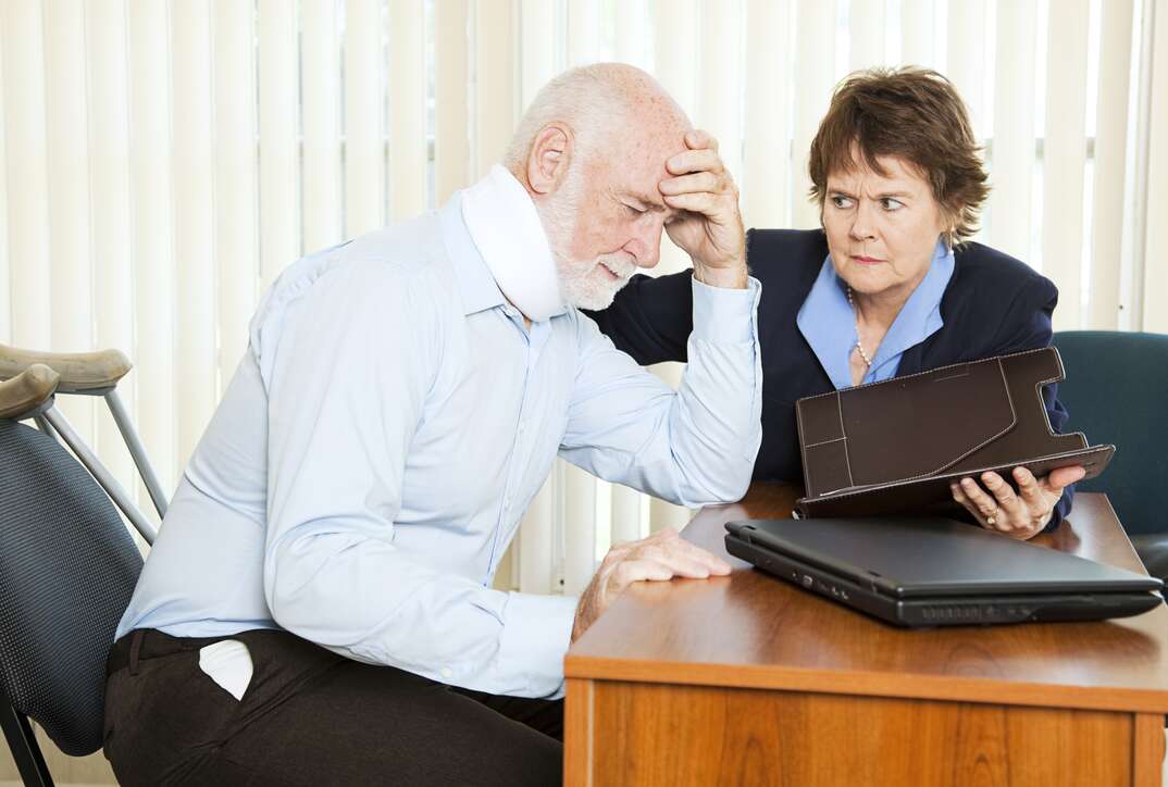 Injured man in pain discussing a lawsuit with his attorney.