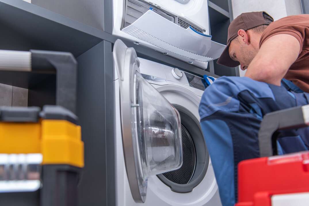 Caucasian Technician in His 40s Repairs Broken Washing Machine. Home Appliances Maintenance.