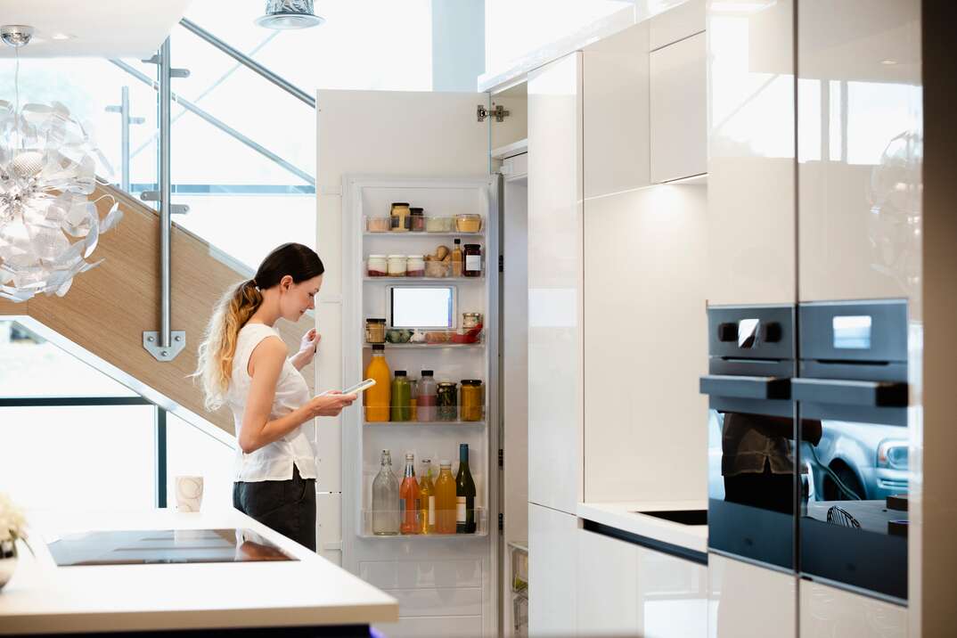 A young woman choosing what healthy snack to get out of her smart fridge 