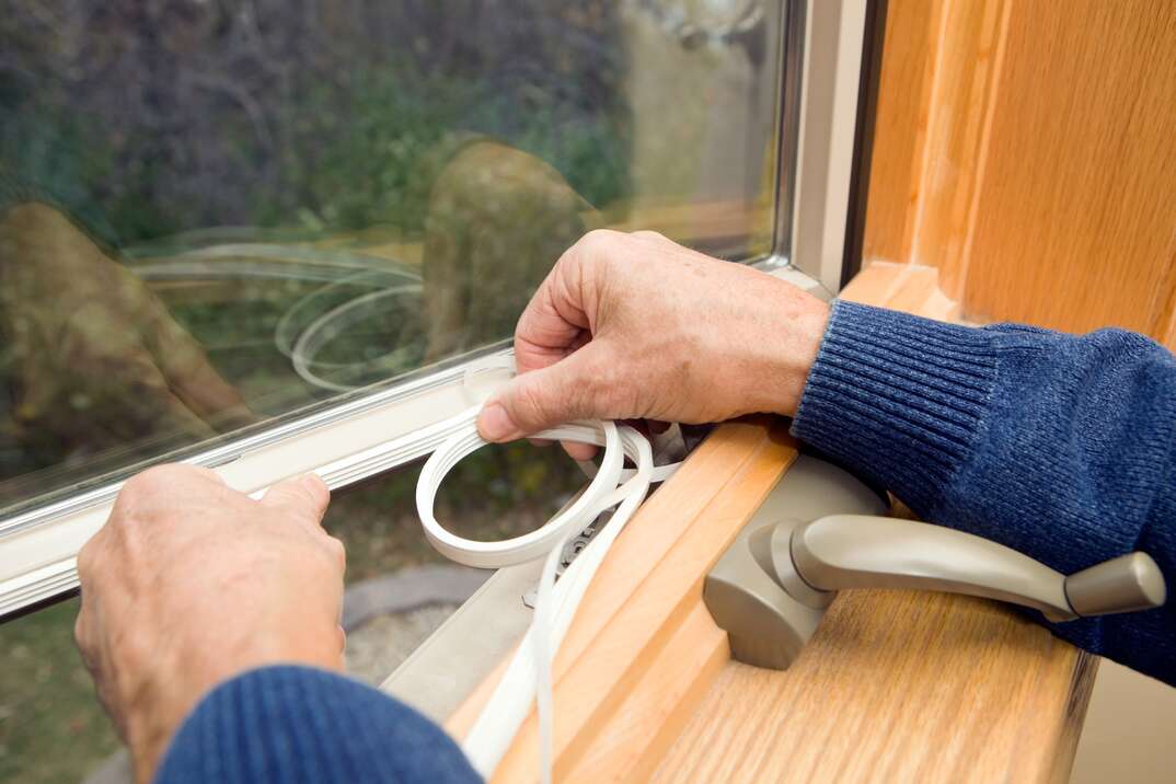 man installing a weather seal onto windows