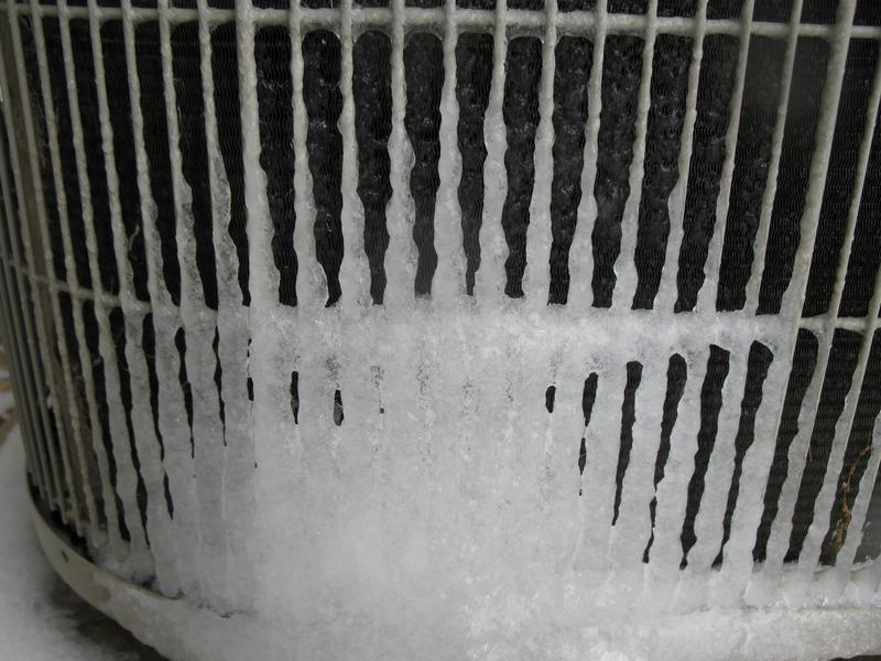 A closeup of an outdoor air conditioning unit that has frozen over, frozen, freezing, freeze, ice, icy, frozen AC unit, frozen HVAC unit, frozen air conditioner, AC unit, air conditioner, hvac unit