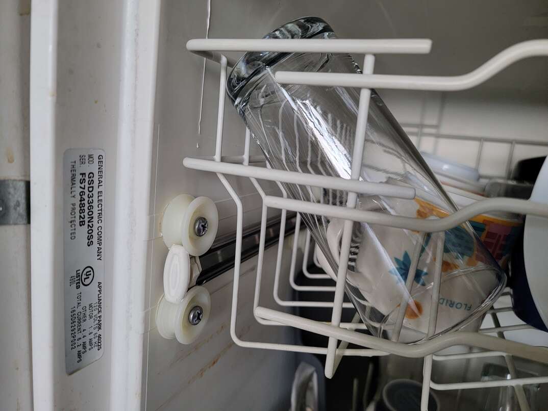 Open door of dishwasher reveals dirty dishes inside as well as where you can find the serial number and model number of the appliance.