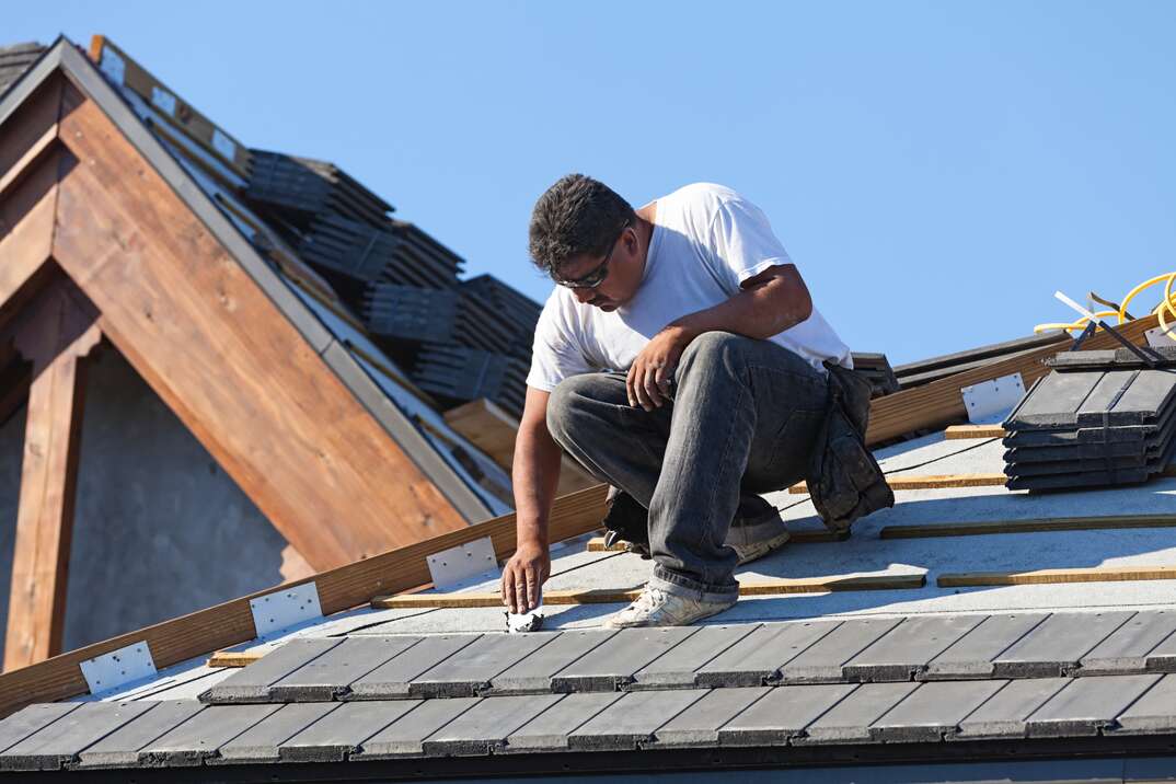 roofing contractor lays new shingles