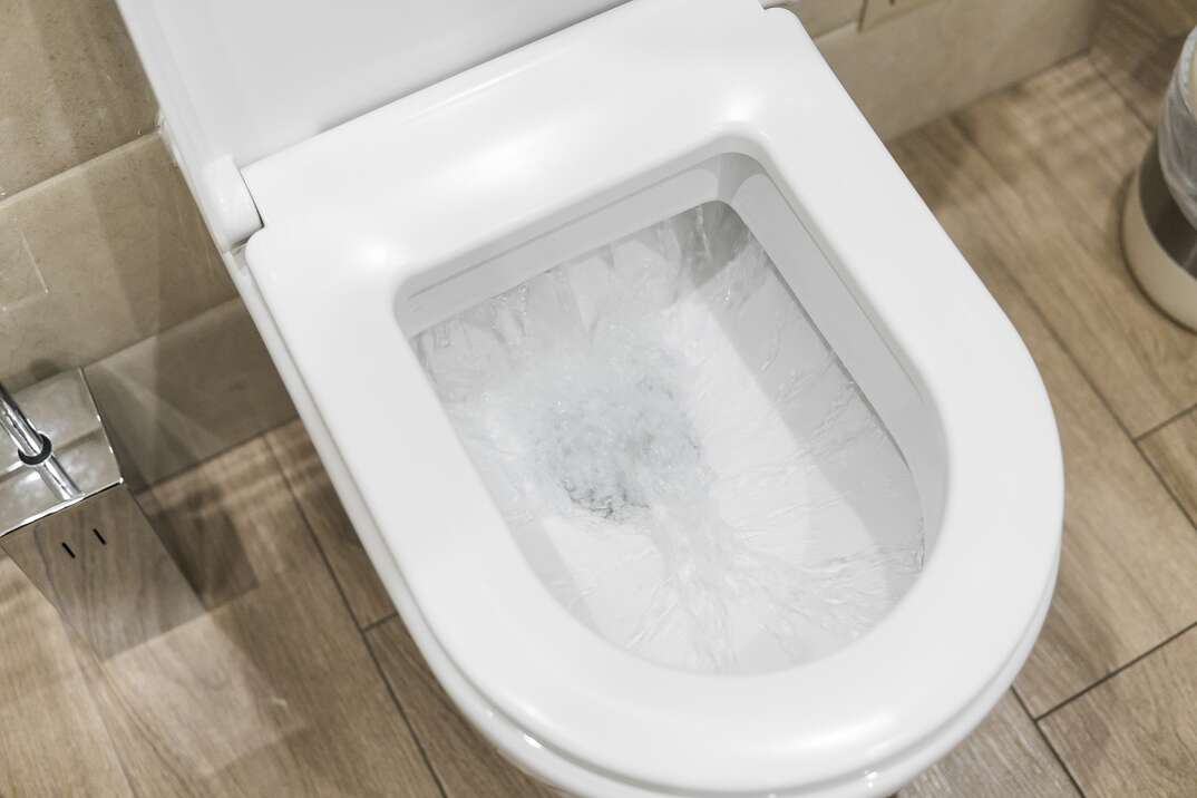 white toilet bowl in bathroom when water is flushed