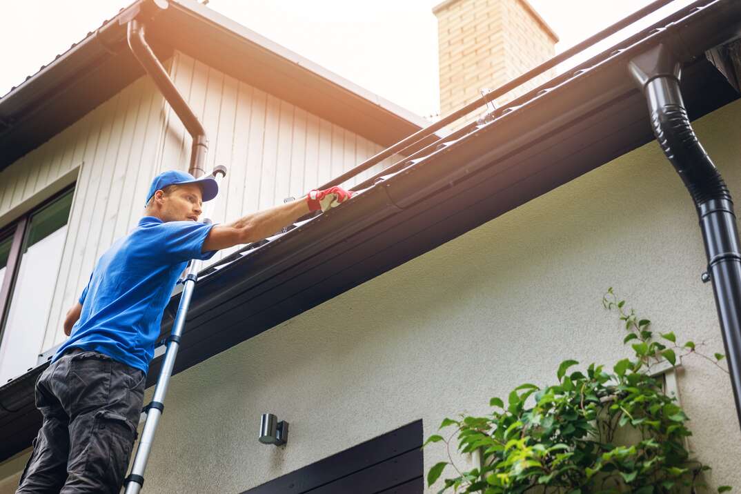 roofer inspecting gutters on a house