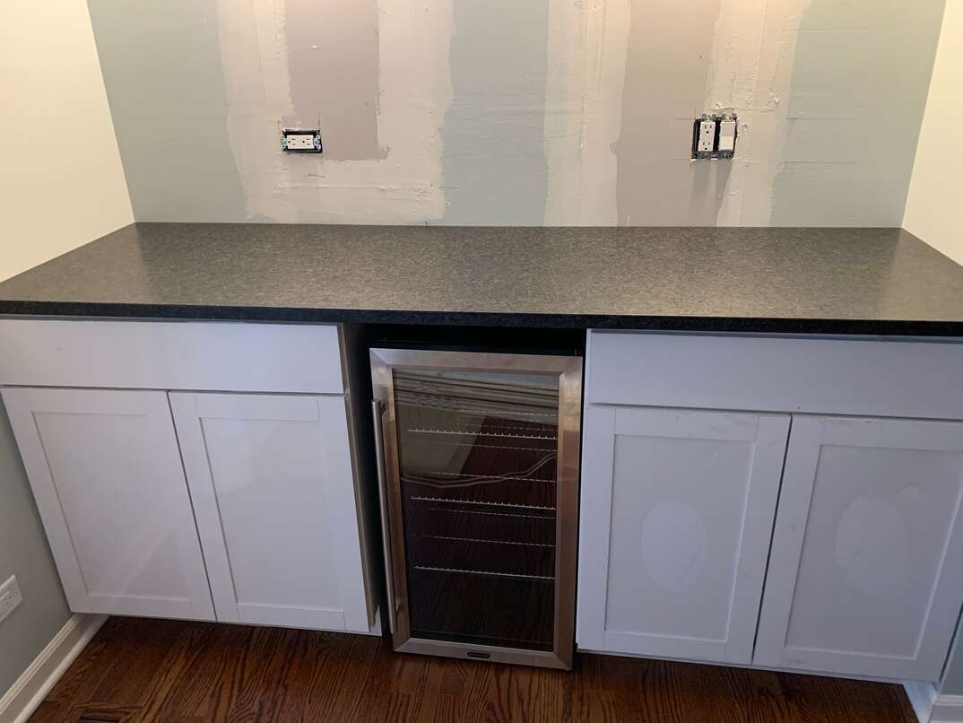 A residential dry bar with a unique  leather  textured black granite counter top