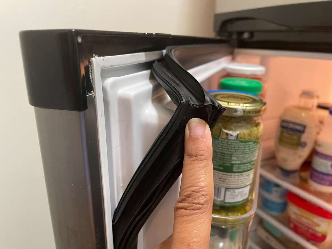Finger points to fridge door seal separating from the doo frame