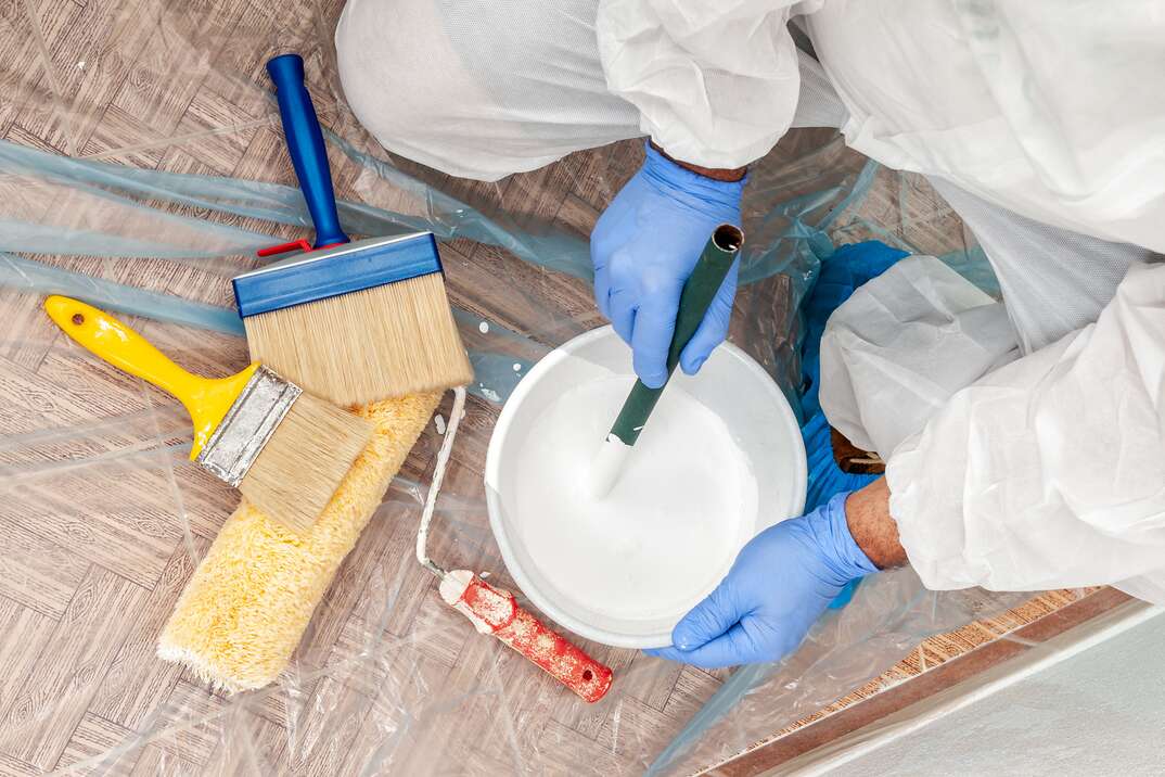 House painter at work mixes paint and water in a container