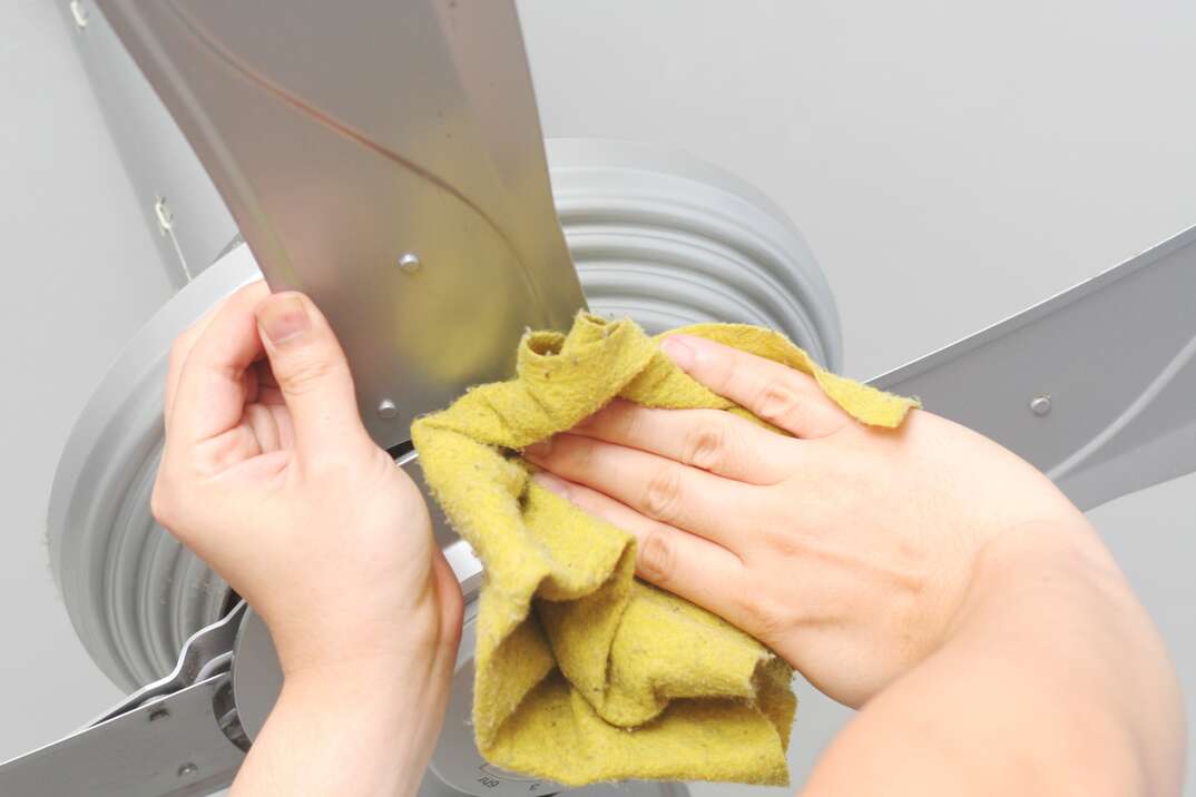 person cleaning ceiling fan